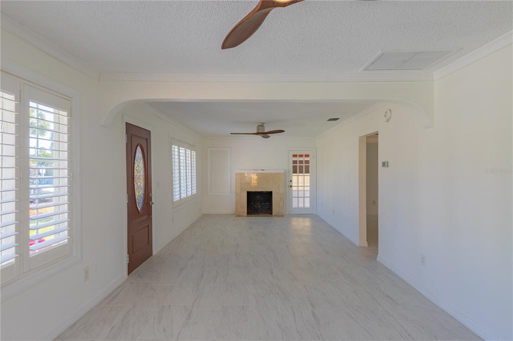 A bright living room features white tile floors, a fireplace, and a front entry door — 944 BRUCE AVENUE, CLEARWATER BEACH, FL