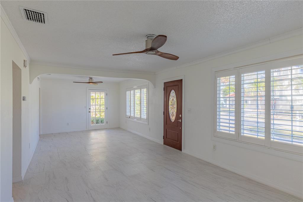 A bright living room with white tile floors, ceiling fans, and a wooden front door — 944 BRUCE AVENUE, CLEARWATER BEACH, FL