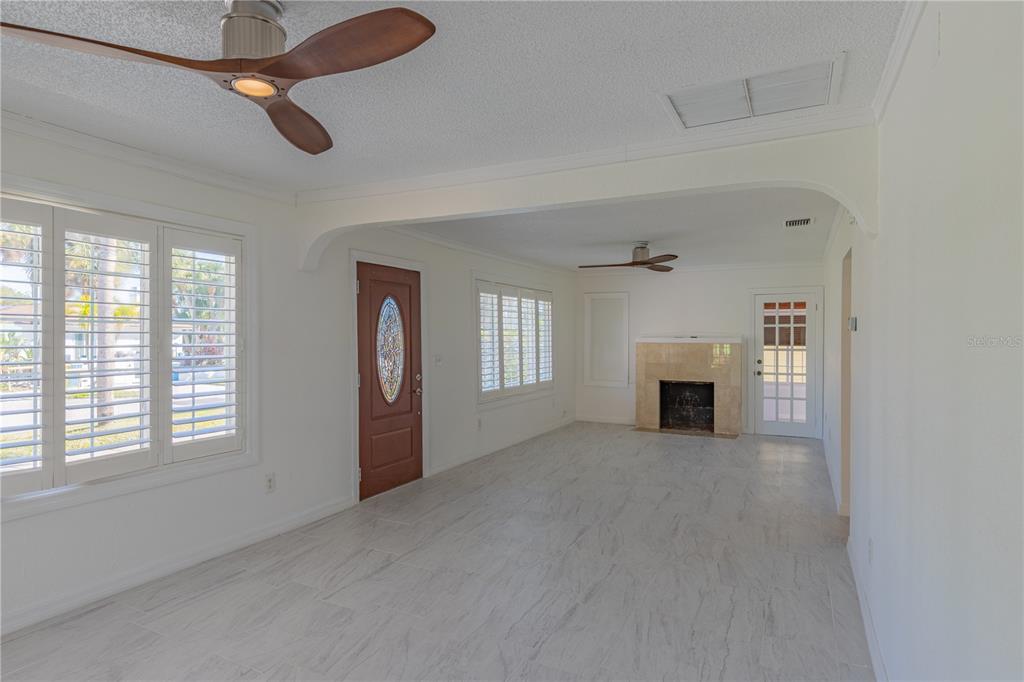 A living room with white tile floors, a fireplace, and two ceiling fans — 944 BRUCE AVENUE, CLEARWATER BEACH, FL