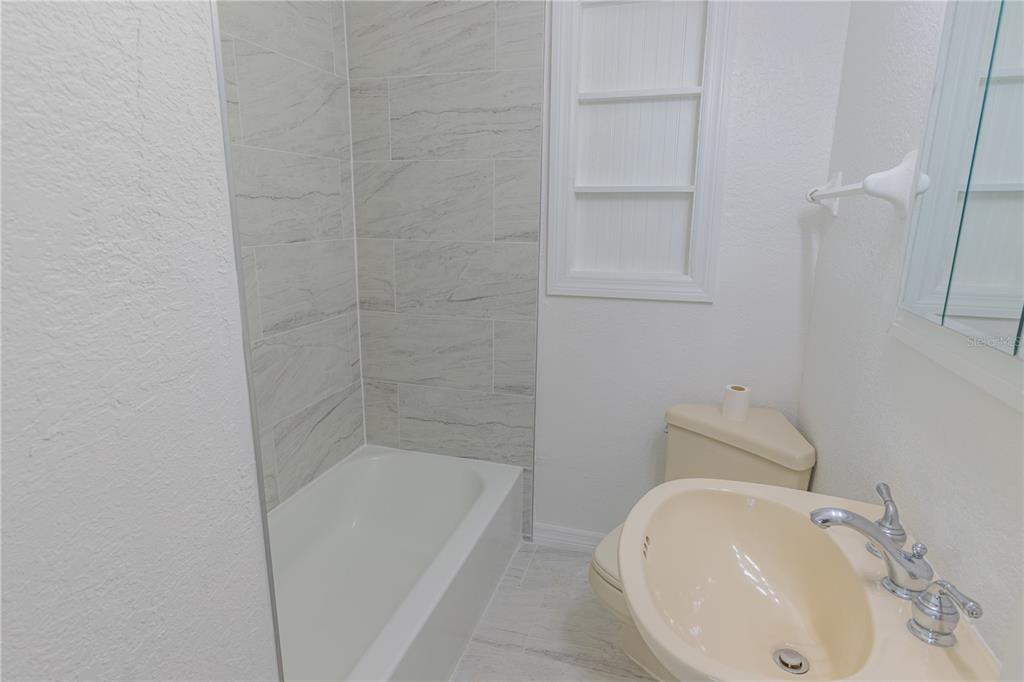 A bathroom features a tiled shower-tub combination, a beige pedestal sink, and a toilet — 944 BRUCE AVENUE, CLEARWATER BEACH, FL