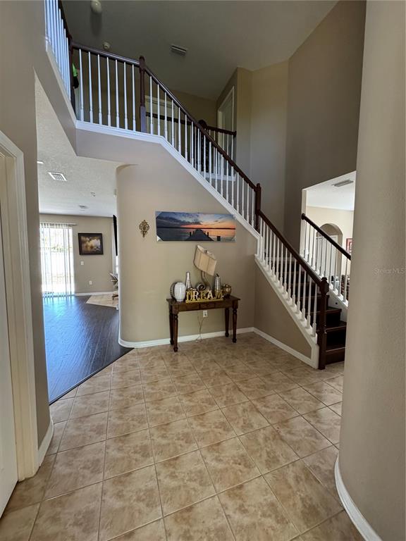 A tiled entryway features a wooden staircase with white railings and a console table — 435 STONE BRIAR DRIVE, RUSKIN, FL