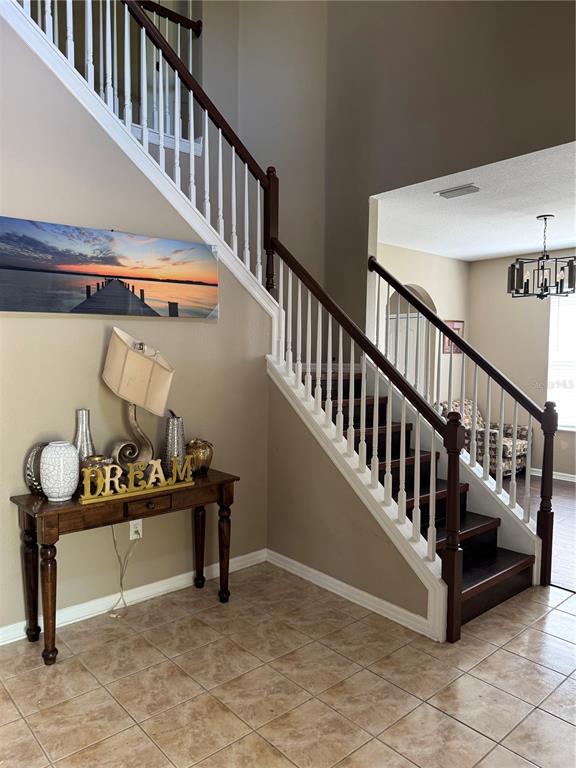 A foyer features a wooden staircase with white balusters, tile flooring, and a console table — 435 STONE BRIAR DRIVE, RUSKIN, FL
