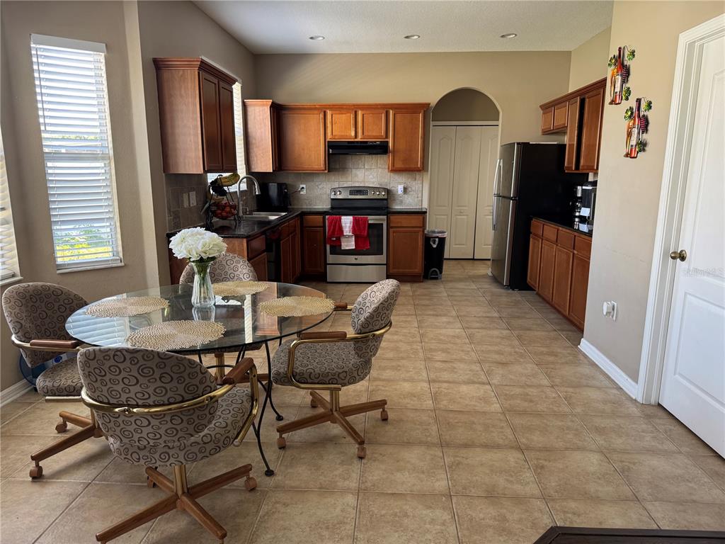 A kitchen with wooden cabinets, stainless steel appliances, and a glass-topped dining table — 435 STONE BRIAR DRIVE, RUSKIN, FL