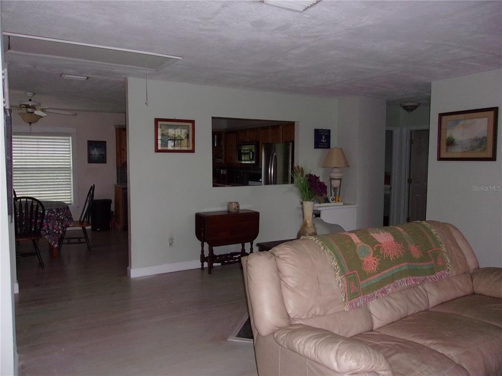 A living room features a beige leather sofa, a pass-through window, and light flooring — 24279 YACHT CLUB BOULEVARD, PUNTA GORDA, FL