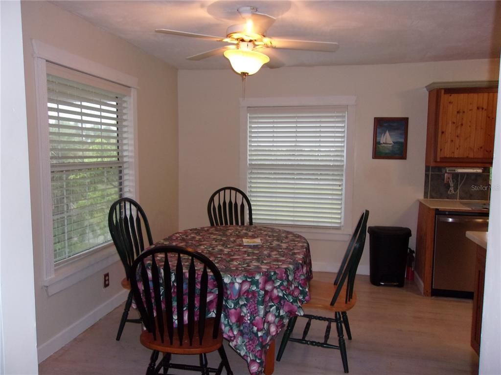 A dining area features a round table with a floral tablecloth, four chairs, and windows — 24279 YACHT CLUB BOULEVARD, PUNTA GORDA, FL