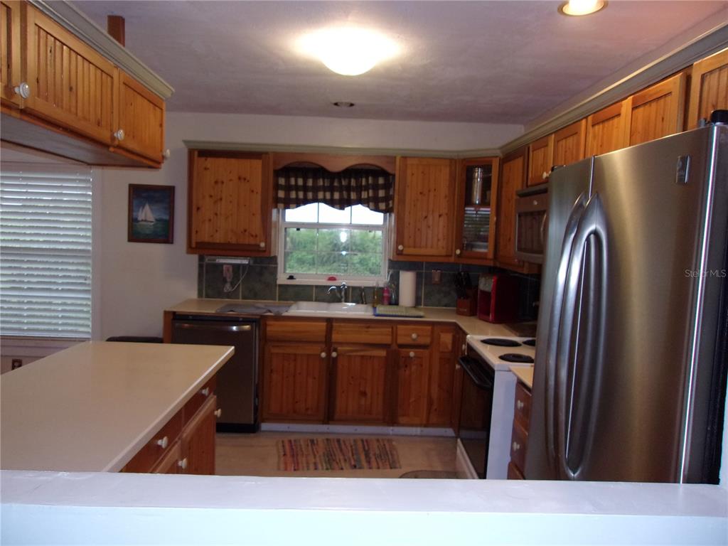 A kitchen features wooden cabinets, stainless steel appliances, and a window above the sink — 24279 YACHT CLUB BOULEVARD, PUNTA GORDA, FL