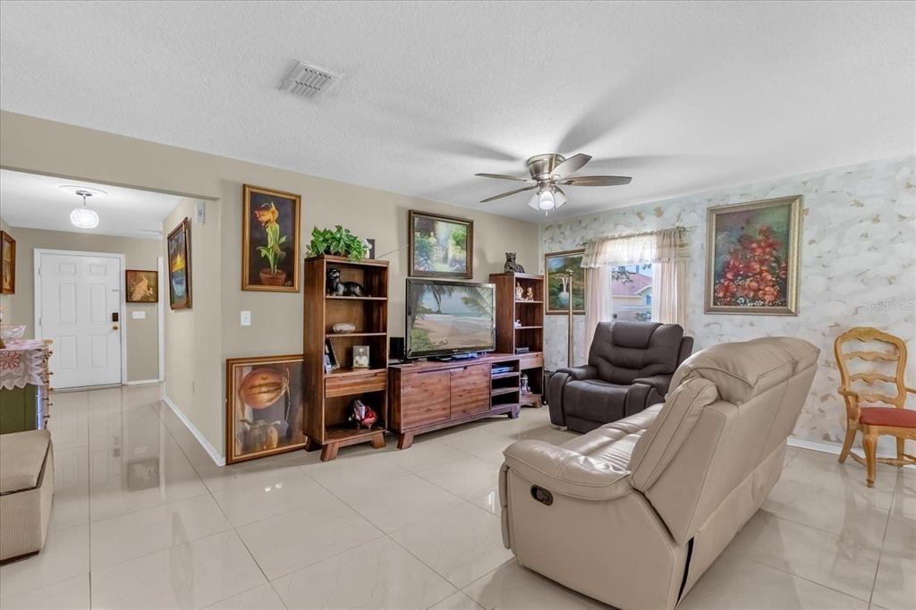 A living room features tile flooring, a ceiling fan, a television console, and recliner seating — 104 VERDI STREET, DAVENPORT, FL