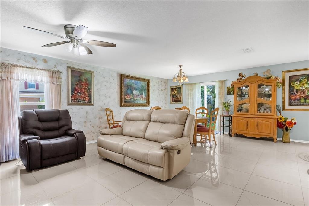 A living and dining room with tile floors, a ceiling fan, and a wooden hutch — 104 VERDI STREET, DAVENPORT, FL