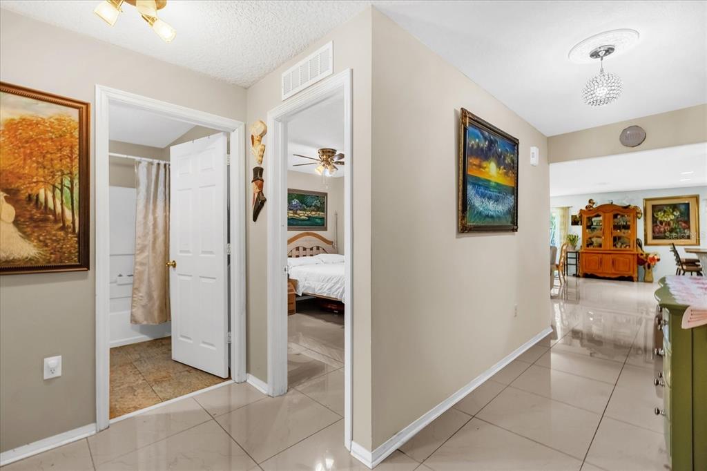 A hallway with beige tile floors leads to a bathroom, a bedroom, and an open area — 104 VERDI STREET, DAVENPORT, FL