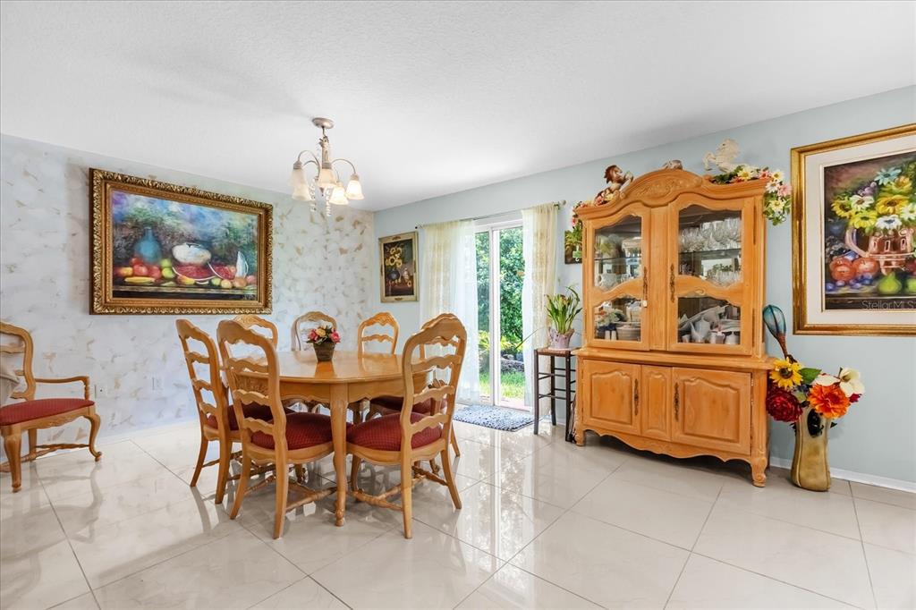 A dining room features a wooden table with chairs, a hutch, and tile flooring — 104 VERDI STREET, DAVENPORT, FL