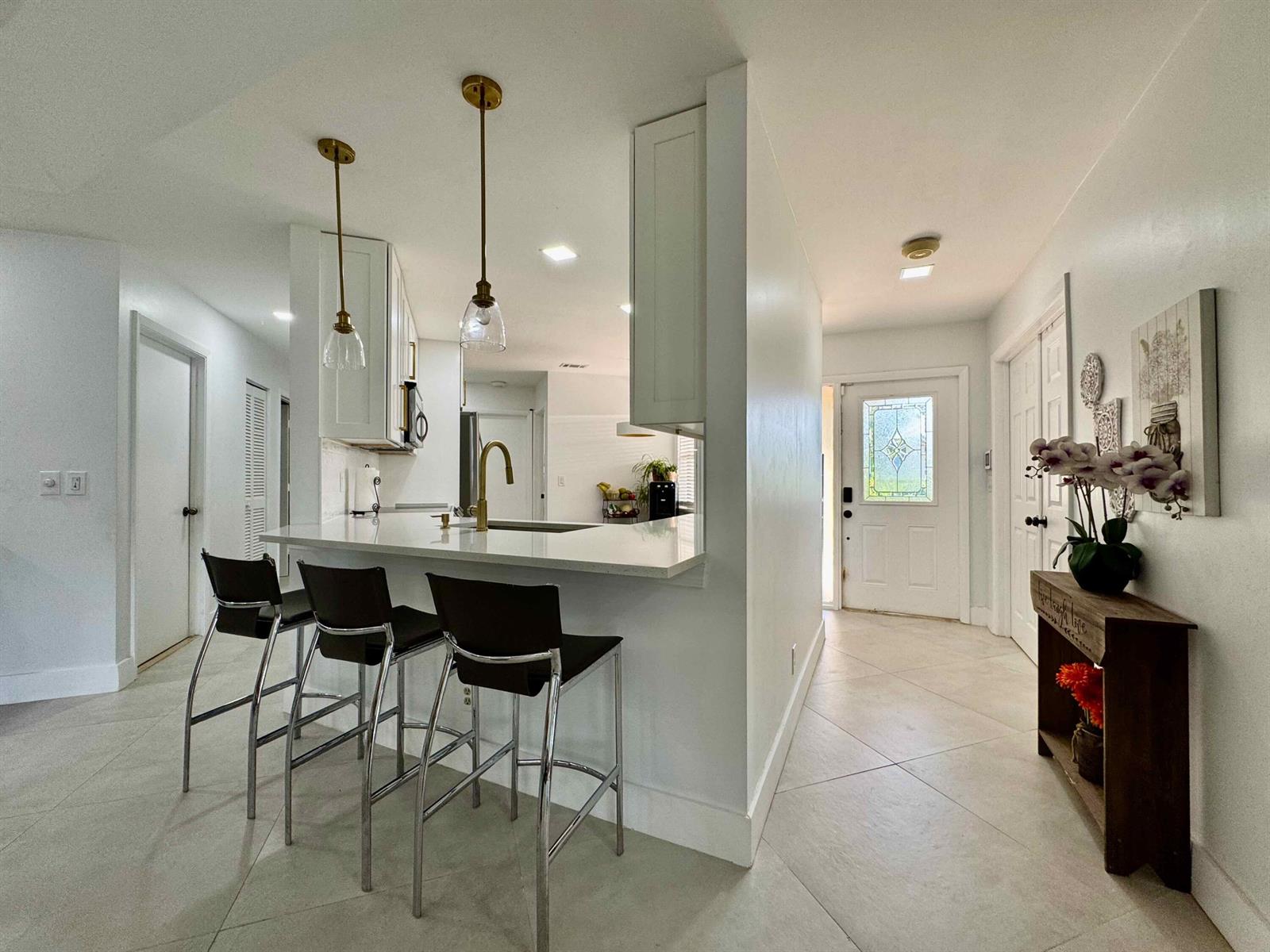 A kitchen with a breakfast bar and pendant lights overlooks an entryway with tile floors — 9106 Chatsworth Cascades, Boca Raton FL 33434, BOCA RATON, FL