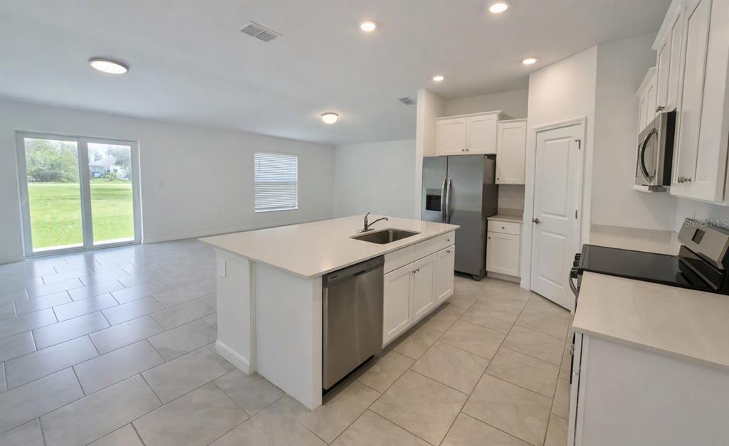 A modern kitchen with white cabinets, stainless steel appliances, and a central island with seating — 23234 ALASKA AVENUE, PORT CHARLOTTE, FL