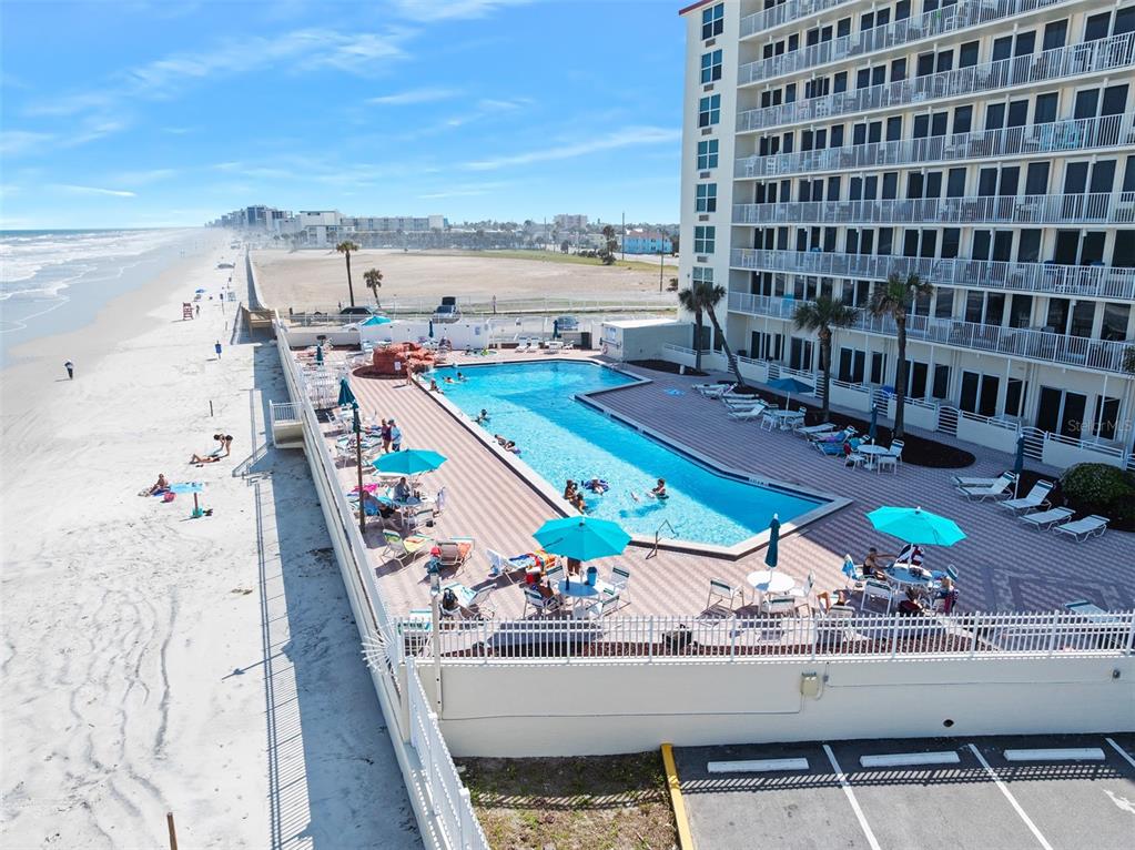 An aerial view shows a beachfront hotel with a swimming pool and lounge chairs — 701 S ATLANTIC AVENUE UNIT 516, DAYTONA BEACH, FL