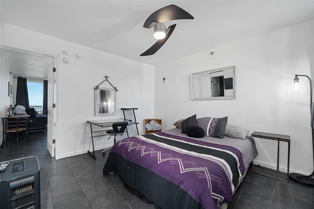 A bedroom with a purple and black bedspread, tile flooring, and a desk area — 701 S ATLANTIC AVENUE UNIT 516, DAYTONA BEACH, FL