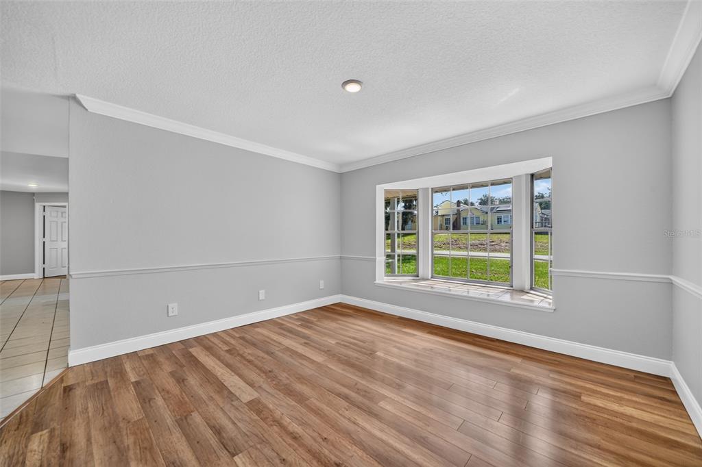 An empty room with light gray walls, wood-look flooring, and a large bay window — 1390 COR JESU COURT, LONGWOOD, FL