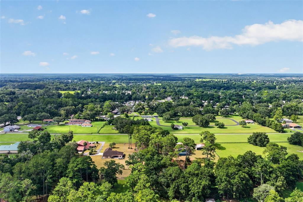 An aerial view shows a rural landscape with scattered houses, green pastures, and dense trees — 8650 SW 27TH AVENUE, OCALA, FL