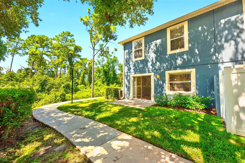 The exterior of a blue two-story townhouse with a concrete patio and a curved walkway — 12905 LEXINGTON SUMMIT STREET, ORLANDO, FL