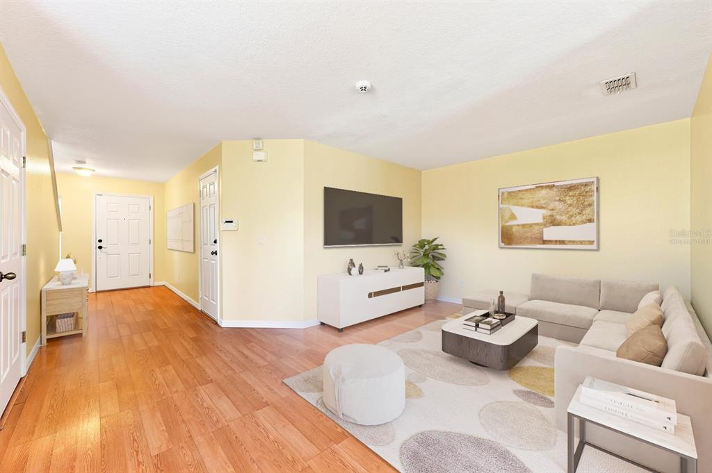 A living room features light yellow walls, wood flooring, a sectional sofa, and a television — 12905 LEXINGTON SUMMIT STREET, ORLANDO, FL