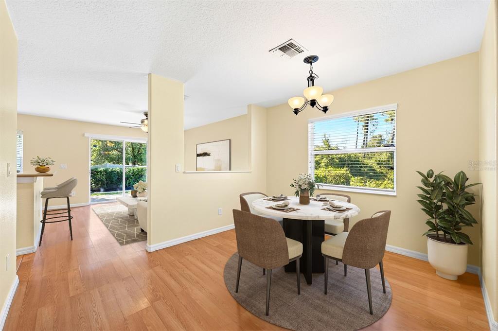 A dining area with a round table and chairs next to a living room space — 12905 LEXINGTON SUMMIT STREET, ORLANDO, FL