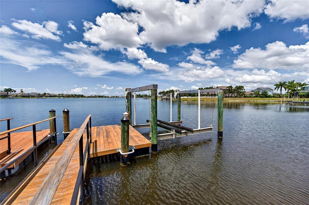 A wooden boat dock with a mechanical boat lift extends into a calm lake — 429 MANNS HARBOR DRIVE, APOLLO BEACH, FL