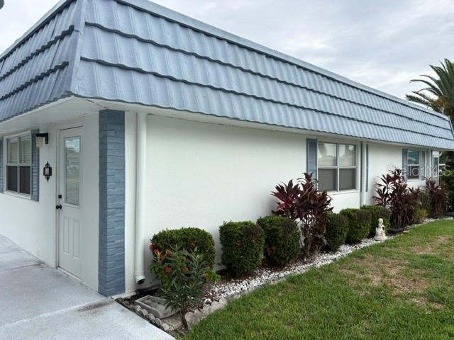 The exterior of a white building features a blue mansard roof and a side entrance — 1901 ANDOVER WAY UNIT 26, SUN CITY CENTER, FL