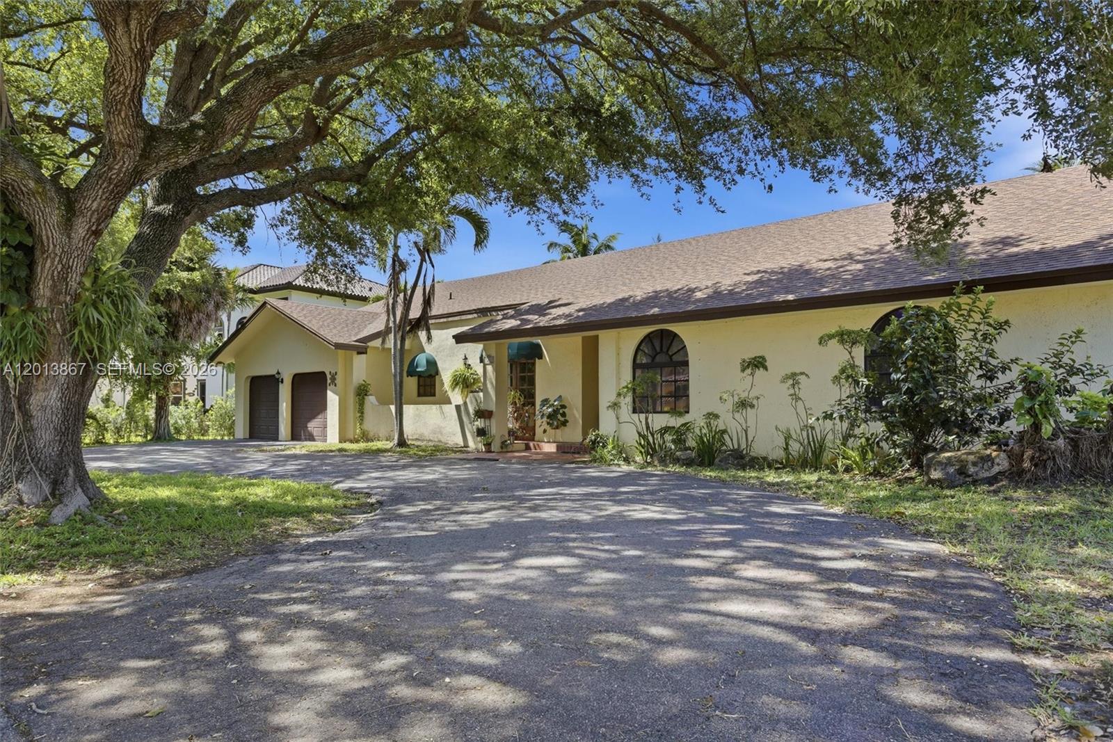 A single-story house with a two-car garage and arched windows sits behind a large tree — 7200 N Oakmont Dr, Hialeah FL 33015, HIALEAH, FL