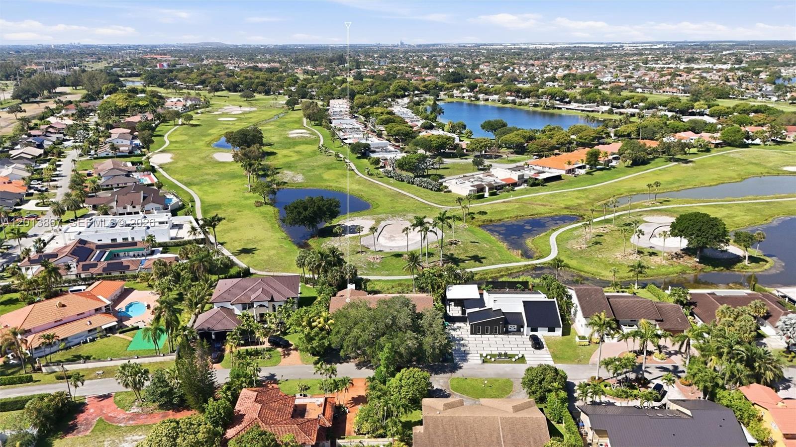 An aerial view shows a residential neighborhood with houses, a golf course, and lakes — 7200 N Oakmont Dr, Hialeah FL 33015, HIALEAH, FL