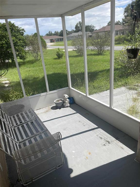 A screened-in porch with a metal bench, a small dog statue, and a grassy yard — 4855 SW 148TH PLACE, OCALA, FL