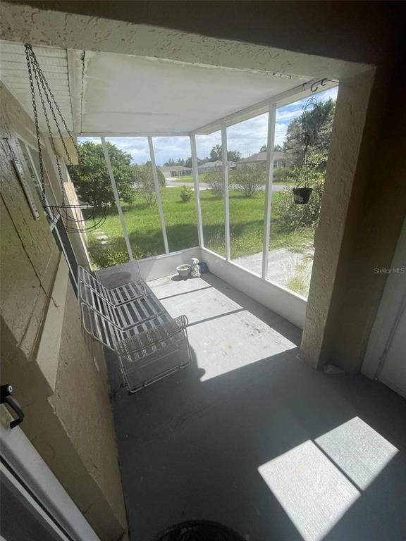 A screened-in porch features a concrete floor, a metal bench, and views of a yard — 4855 SW 148TH PLACE, OCALA, FL