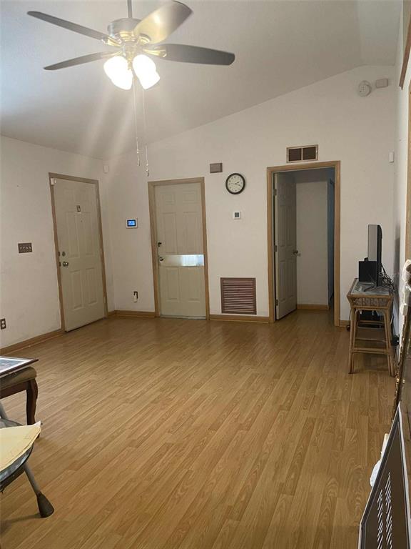 A room with wood-look flooring, a ceiling fan, two doors, and an open doorway — 4855 SW 148TH PLACE, OCALA, FL
