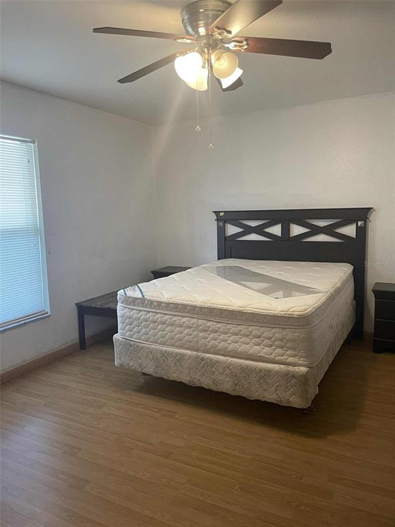 A bedroom features a dark wood headboard, a mattress on a box spring, and wood flooring — 4855 SW 148TH PLACE, OCALA, FL
