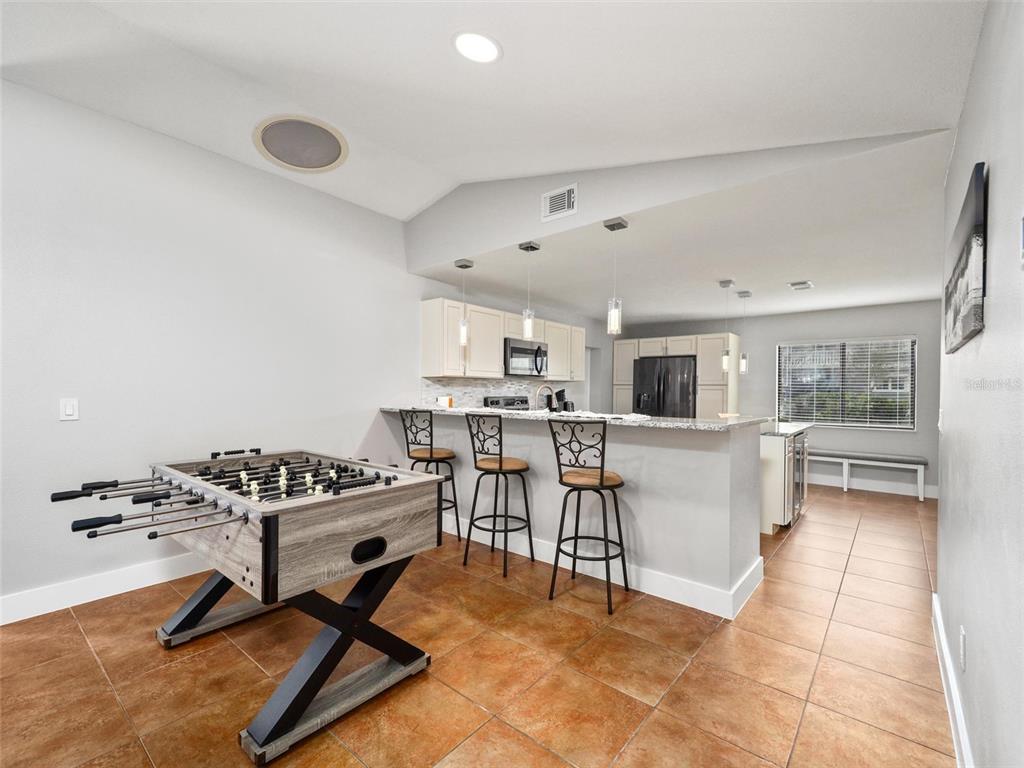 A foosball table sits in a kitchen area with a breakfast bar and tile flooring — 2 CEDAR COURT, PALM COAST, FL