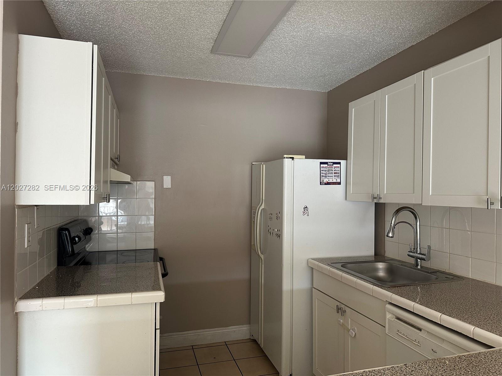 A kitchen features white cabinets, a refrigerator, a stove, a sink, and tiled countertops — 890 SW 129th Pl # 208, Miami FL 33184, MIAMI, FL