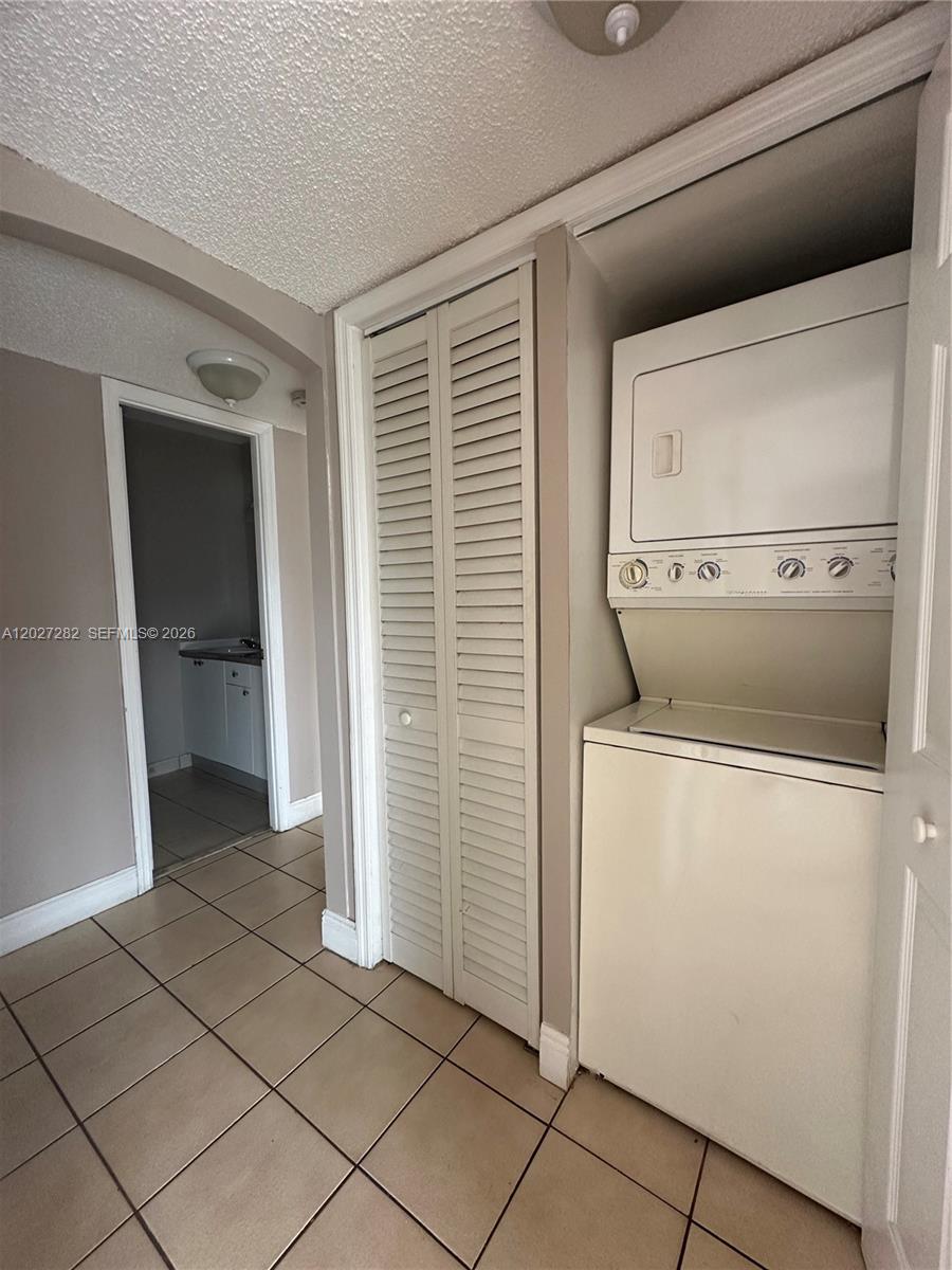 A laundry area features a stacked washer and dryer next to a louvered closet door — 890 SW 129th Pl # 208, Miami FL 33184, MIAMI, FL