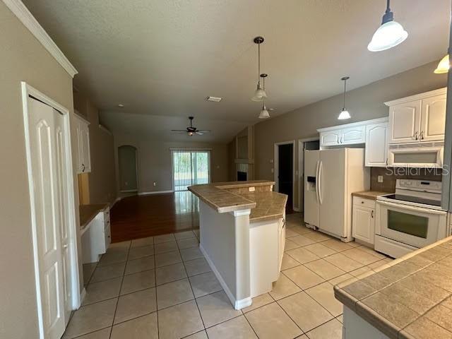 A kitchen with white cabinets, tile flooring, and a breakfast bar overlooks an open living area — 31 RYMER LANE, PALM COAST, FL