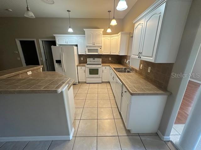 A kitchen with white cabinets, tile countertops, and a white refrigerator — 31 RYMER LANE, PALM COAST, FL