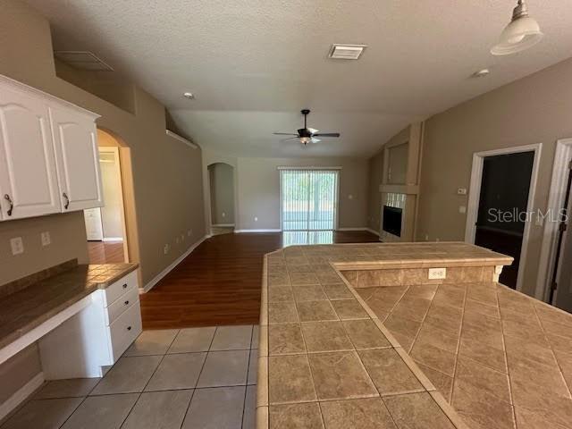 A kitchen with tiled countertops overlooks a living area with wood flooring and a ceiling fan — 31 RYMER LANE, PALM COAST, FL