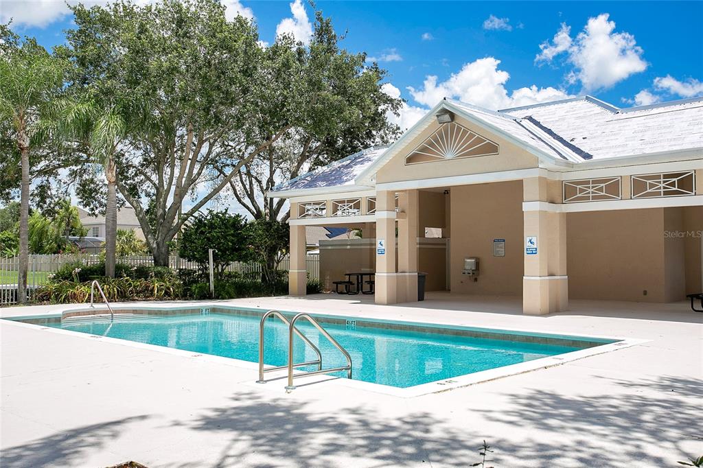A rectangular swimming pool sits in front of a covered outdoor pavilion with beige columns — 13324 FAIRWAY GLEN DRIVE UNIT 101, ORLANDO, FL