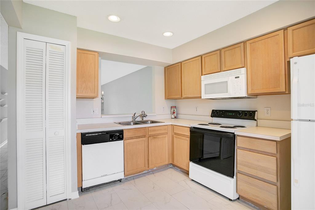 A kitchen with light wood cabinets, white appliances, and light-colored tile flooring — 13324 FAIRWAY GLEN DRIVE UNIT 101, ORLANDO, FL