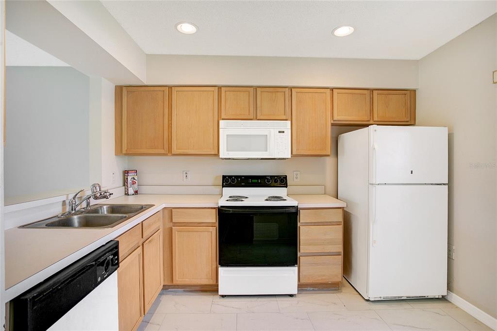 A kitchen features light wood cabinets, white countertops, a white stove, and a white refrigerator — 13324 FAIRWAY GLEN DRIVE UNIT 101, ORLANDO, FL