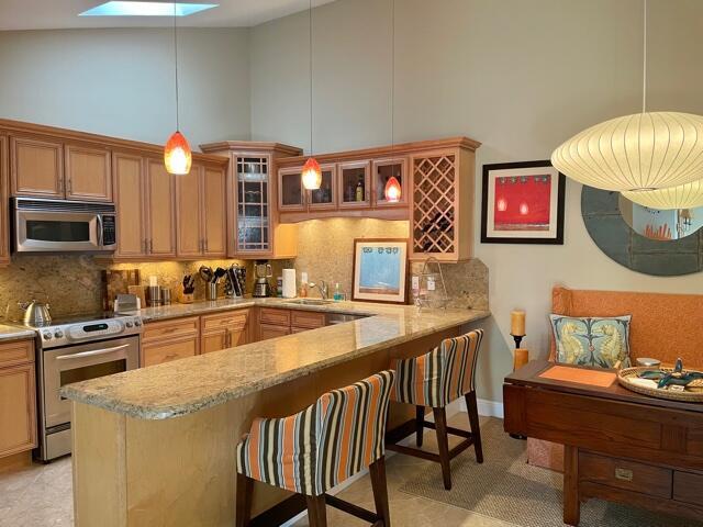 A kitchen features light wood cabinets, granite countertops, a breakfast bar, and striped stools — 1801 S Us Highway 1 # 17c, Jupiter FL 33477, JUPITER, FL