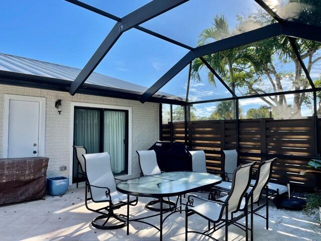 A screened-in patio features a glass-topped dining table with chairs and a brick exterior — 1801 S Us Highway 1 # 17c, Jupiter FL 33477, JUPITER, FL
