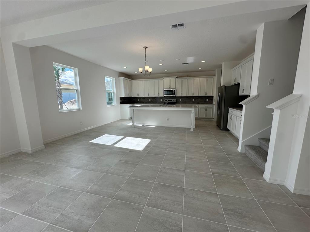 An open-concept kitchen and living area features white cabinetry, a central island, and tile flooring — 2000 BEEVALLEY WAY, DELAND, FL