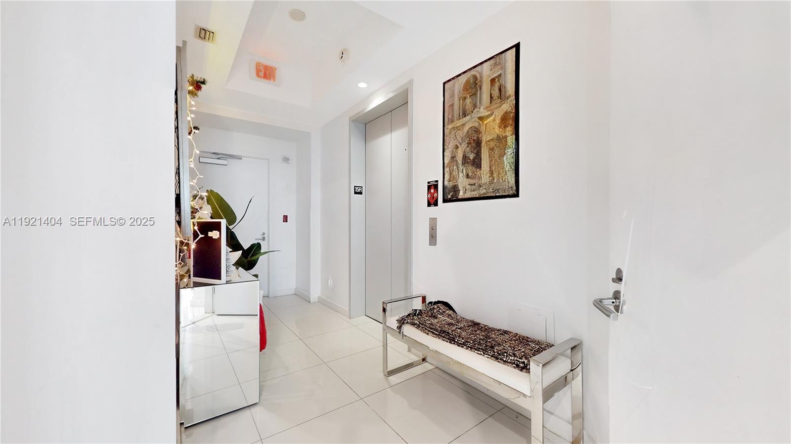 A bright hallway features white tile floors, a modern bench, and an elevator entrance — 851 NE 1st Ave # 1508, Miami FL 33132, MIAMI, FL