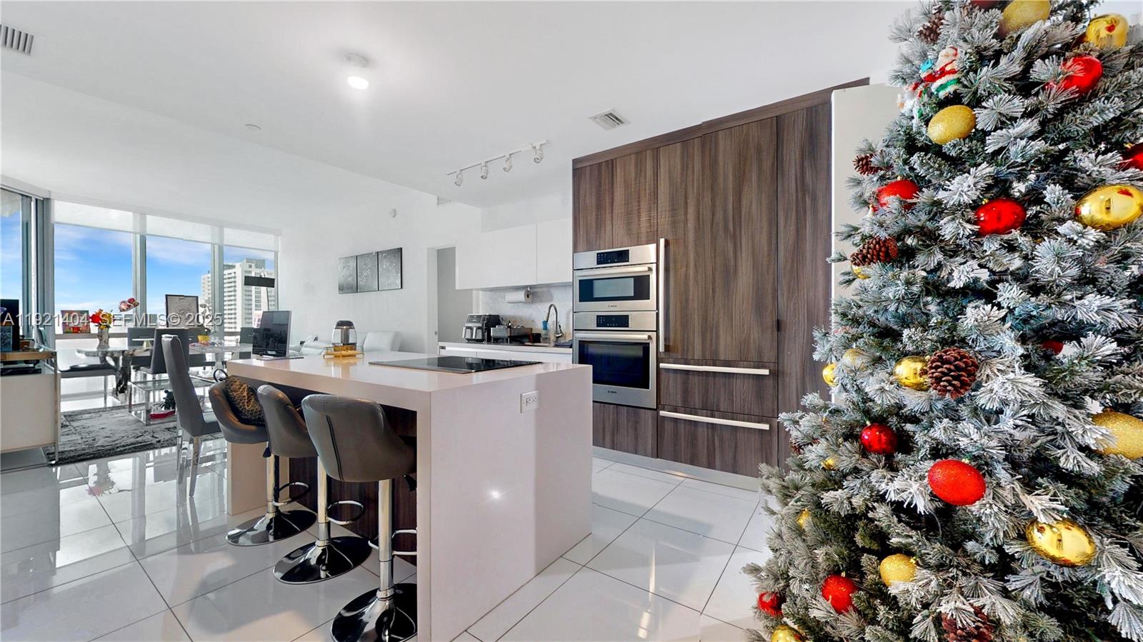 A modern kitchen features a white island with bar stools and dark wood cabinetry — 851 NE 1st Ave # 1508, Miami FL 33132, MIAMI, FL