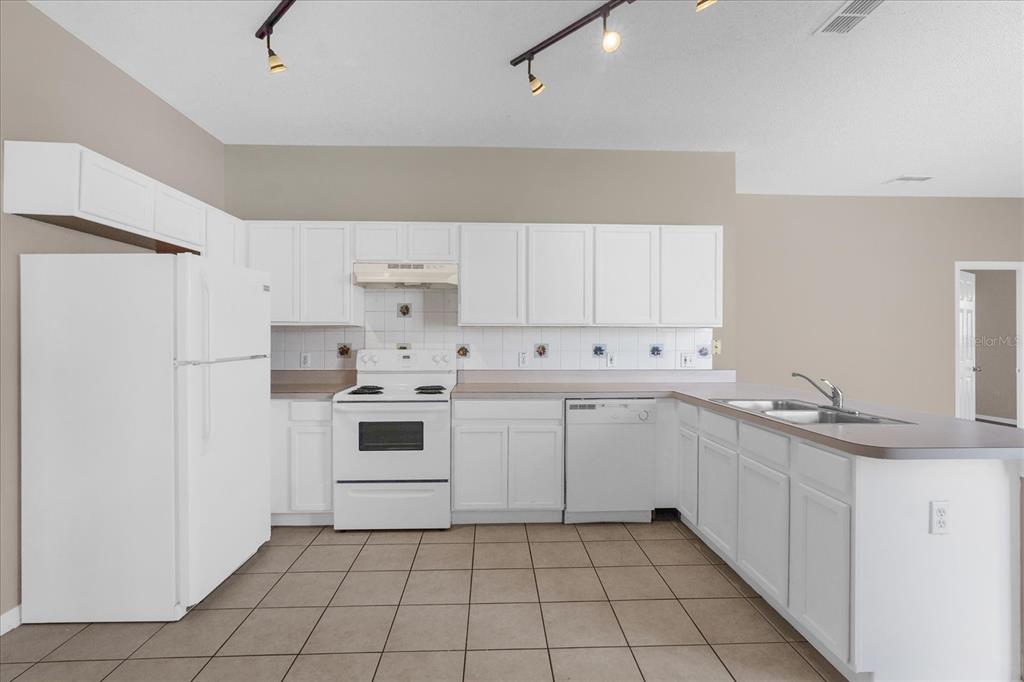 A kitchen with white cabinets, white appliances, a tiled floor, and a breakfast bar — 29 ANDORA COURT, KISSIMMEE, FL