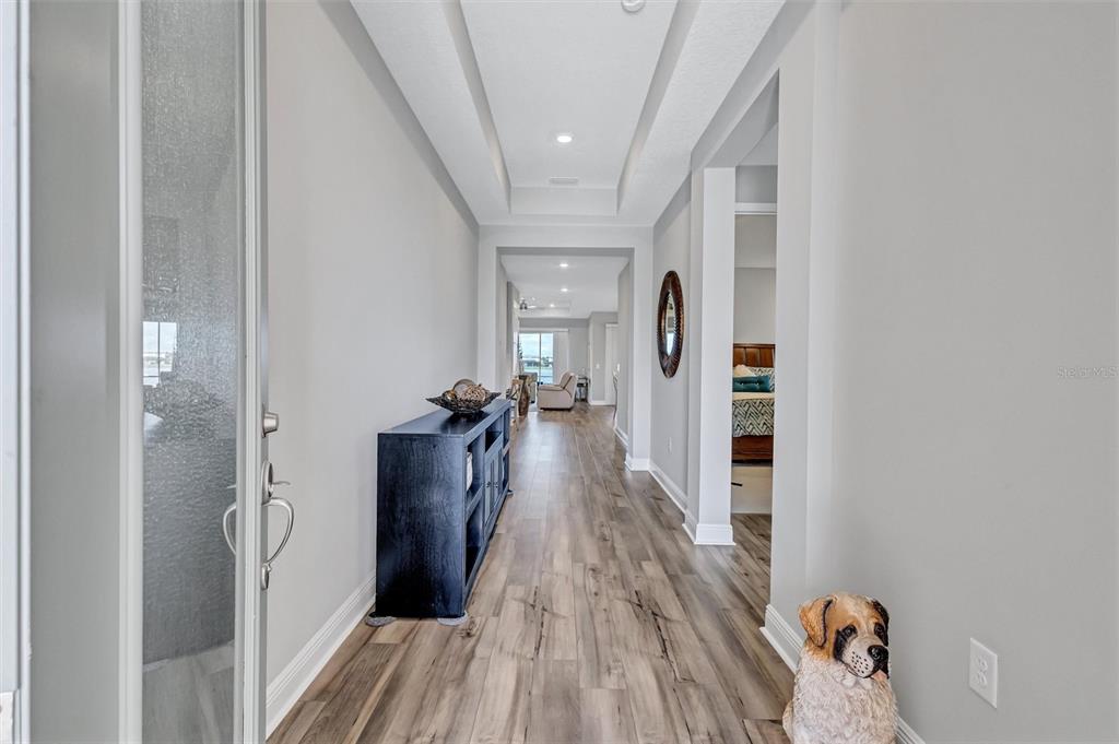 A hallway with wood-look flooring leads from the entryway toward a living area — 17241 SAVORY MIST CIRCLE, BRADENTON, FL