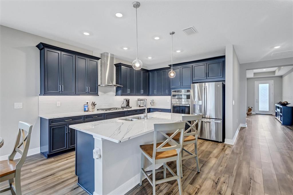 A kitchen features dark blue cabinets, a white marble island, and stainless steel appliances — 17241 SAVORY MIST CIRCLE, BRADENTON, FL