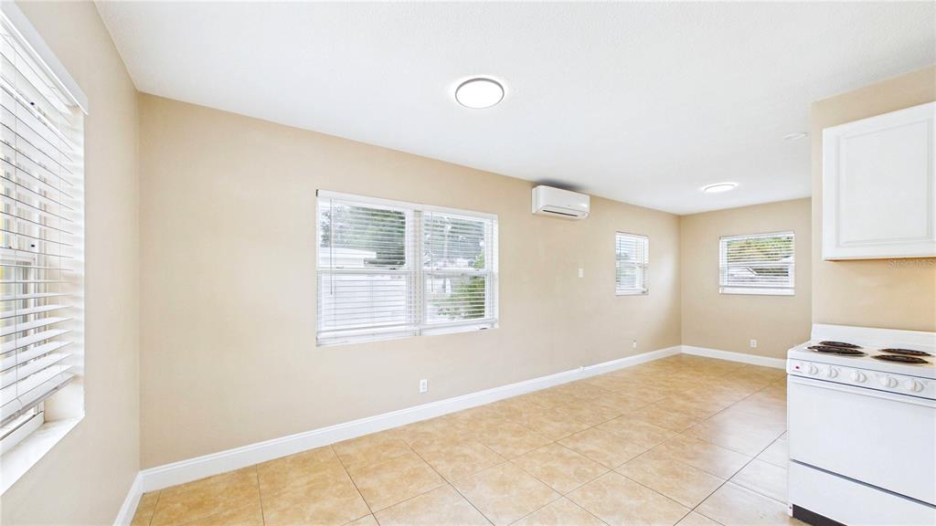 A bright living room features a daybed, tile flooring, and a white kitchen stove — 3815 1ST AVE N UNIT C, ST PETERSBURG, FL