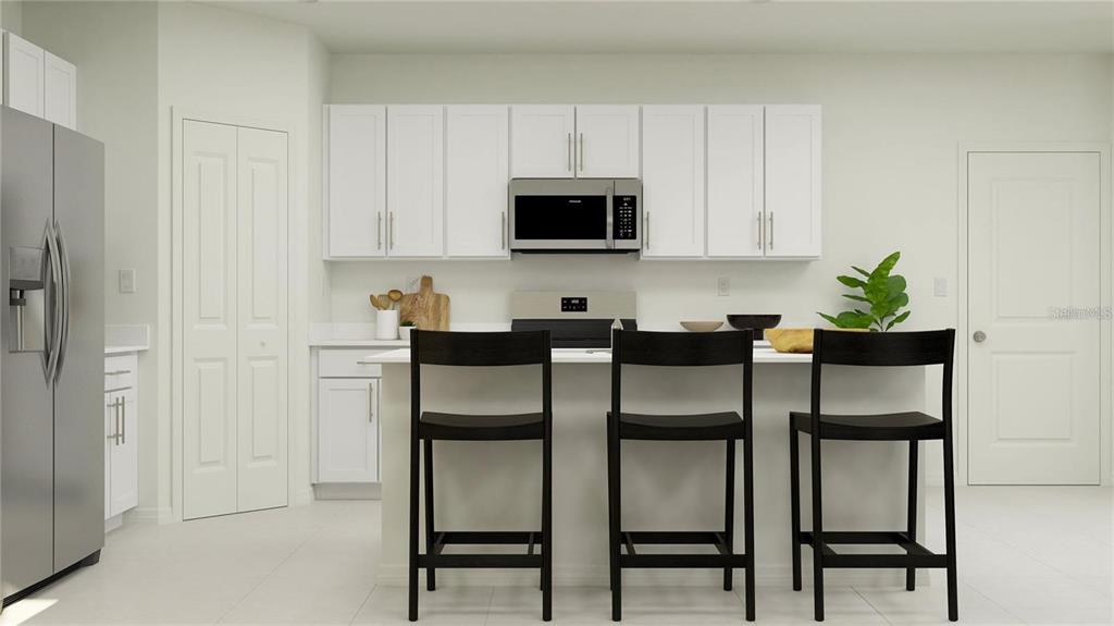 A modern kitchen features white cabinetry, stainless steel appliances, and a central island with stools — 11851 NOBLE CHASE PATH, DADE CITY, FL